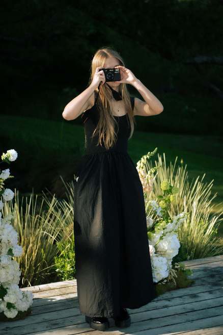 A creator filming in an elegant black gown